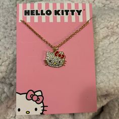 the hello kitty necklace is on display in front of a pink card with a hello kitty charm