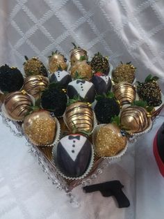 a box filled with chocolate covered strawberries in gold and black decorations on top of a white table cloth