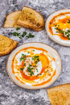 two white plates topped with food next to slices of bread