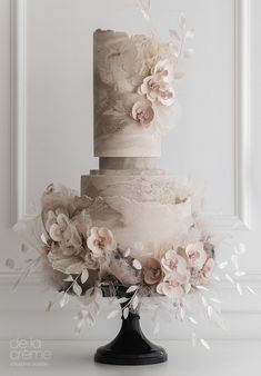 a three tiered wedding cake with flowers on top