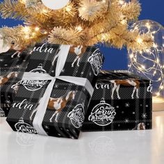 presents wrapped in black and white wrapping paper under a christmas tree with lights on it