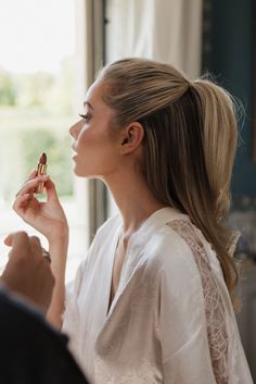 a woman is getting her make - up done in front of a window and looking out the window