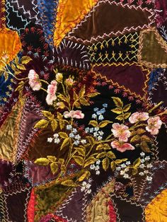 a close up view of a quilt with many different colors and designs on it, including flowers