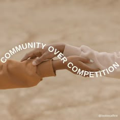 two hands holding each other with the words community over competition written in white on them