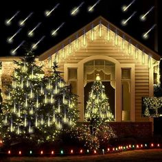 a house with christmas lights on the front and trees in the yard at night time