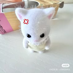 a small white stuffed animal sitting on top of a table