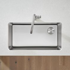 a stainless steel kitchen sink on top of a wooden floor next to a faucet