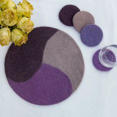 flowers are sitting next to two round rugs on a white surface with purple and grey colors