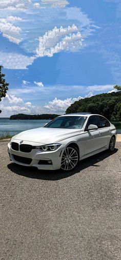 a white car is parked in front of the water