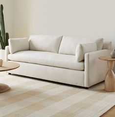 a white couch sitting on top of a wooden table next to a potted plant