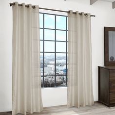 the curtains are hanging in front of a large window with cityscape behind them