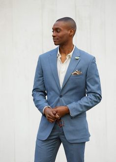 a man in a blue suit and white shirt is looking off to the side with his hands in his pockets