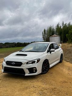 a white subarunt is parked in the dirt