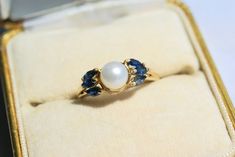 a pearl and sapphire ring in a box