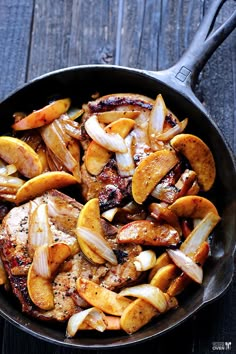 a skillet filled with meat and onions on top of a wooden table