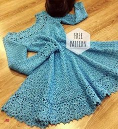 a blue crocheted dress sitting on top of a wooden floor