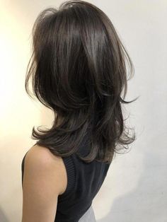 the back of a woman's head with long dark brown hair and black top