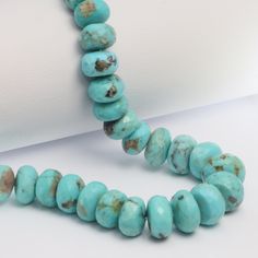 a necklace made with turquoise beads on a white surface and an object in the background