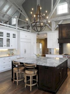 a large kitchen with white cabinets and an island in the middle, surrounded by stools