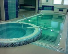 an indoor swimming pool with tiled walls and flooring, including a circular jacuzzi tub