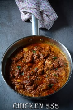 a pan filled with meat and sauce on top of a black counter next to a napkin