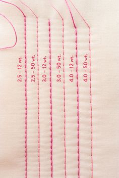 a close up of a piece of cloth with stitching on it and numbers written in pink thread