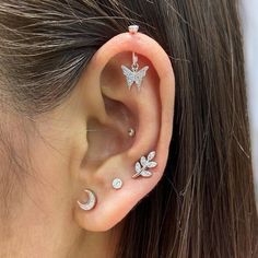 a woman's ear with three piercings and a butterfly on top of it