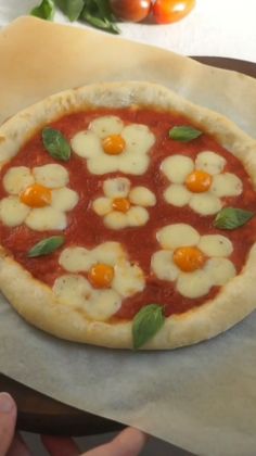 a pizza with cheese and tomato sauce on it is sitting on wax paper next to some tomatoes