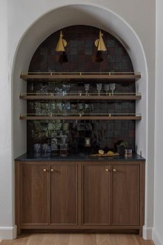 an arched doorway leads into a kitchen with wooden cabinets and black counter tops, along with brass - plated lights