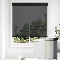 a white room with a window covered in black shades and plants on the windowsill