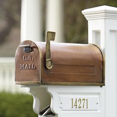 a close up of a mailbox on the side of a white building with trees in the background