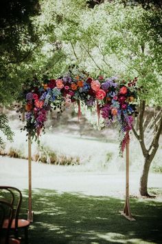 an arch decorated with flowers and greenery for a wedding ceremony in the shade of trees