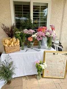 a table topped with vases filled with flowers next to a white table cloth covered table