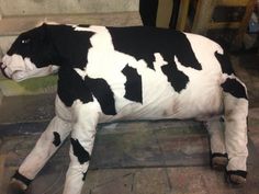 a statue of a black and white cow laying on the ground