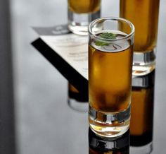 three glasses filled with liquid sitting on top of a table