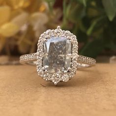 an engagement ring with a cushion cut diamond surrounded by pave diamonds