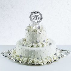 a three tiered wedding cake with white flowers on the bottom and silver trimmings