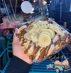 a person holding up a plastic container with bananas and caramel on it in front of a car