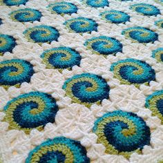 a crocheted blanket with blue and green circles on it