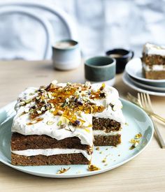 a piece of carrot cake with white frosting on a plate next to two forks