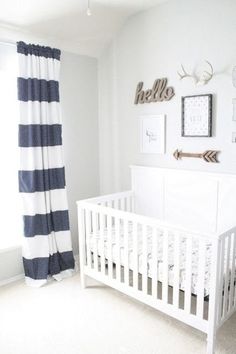 a baby's room with a white crib and striped curtains