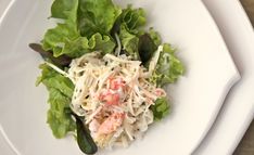 a white plate topped with lettuce and shrimp salad