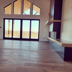 an empty living room with wood floors and large windows