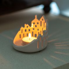 a candle that is sitting on a table with some buildings in the backround