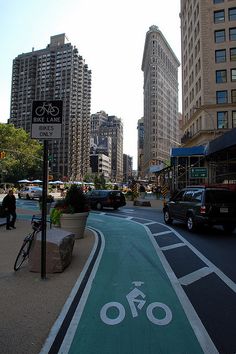 a bike lane painted on the side of a city street with buildings in the background