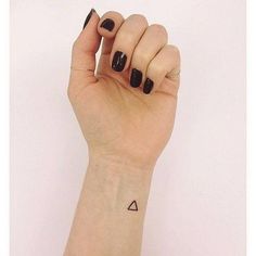 a woman's hand with a small triangle tattoo on her left wrist and black nail polish