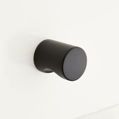 a black knob on the side of a white wall