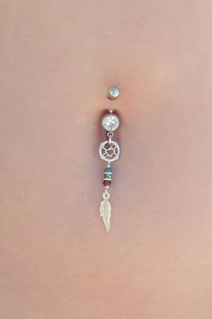 the back of a woman's stomach with a belly ring and dangling bead