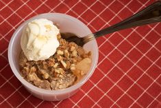 a bowl filled with ice cream next to a spoon on top of a red table cloth