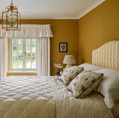 a bedroom with yellow walls, white bedding and two lamps on either side of the bed